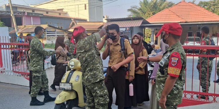 Babinsa Kodim Kendari saat membagikan masker kepada pelajar antisipasi kabut asapa akibat karhutla